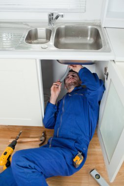 Portrait of a smiling plumber fixing a sink clipart