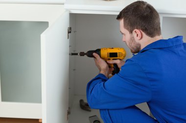 Young handyman fixing a door clipart