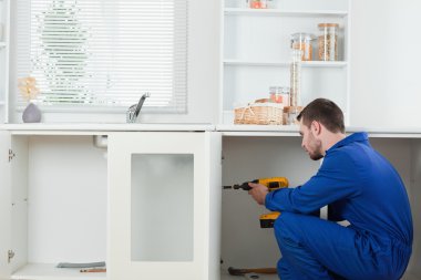 Handsome handyman fixing a door clipart