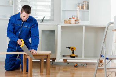 Young handyman cutting a wooden board clipart