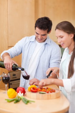 Portrait of a cute man pouring a glass of wine while his wife is clipart