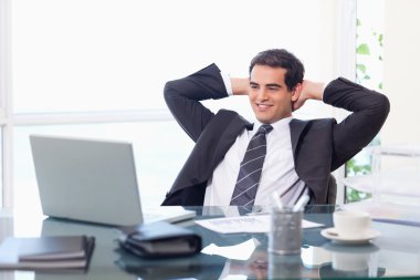 Relaxed businessman working with a laptop clipart