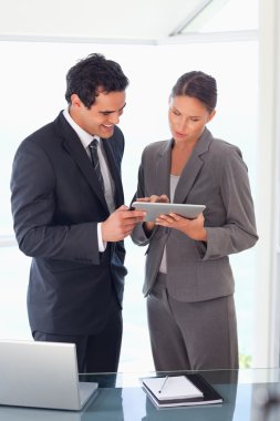 Business partner looking at tablet together clipart