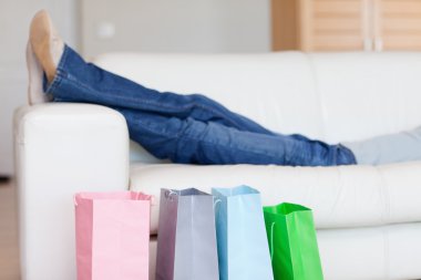 Female legs resting on sofa after shopping tour clipart