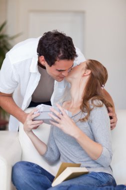 Woman giving her boyfriend a small kiss as thanks for a present clipart