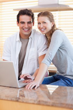 Smiling couple with notebook in the kitchen clipart