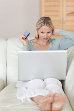 Woman on the sofa hunting bargain online clipart