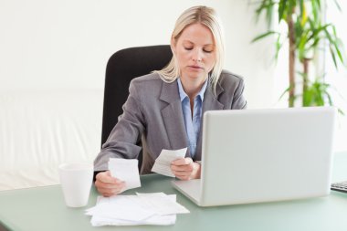 Businesswoman comparing bills clipart