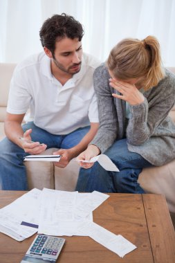 Portrait of a sad couple looking at their bills clipart