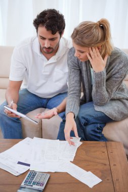 Portrait of a worried couple looking at their bills clipart