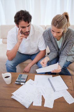 Portrait of a worried young couple doing their accounting clipart