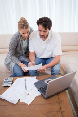 Portrait of a couple doing their accounting with a laptop clipart