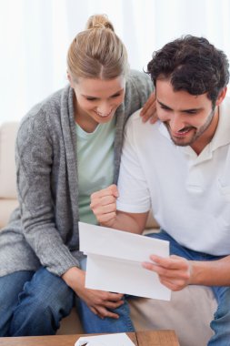 Portrait of a delighted couple reading a letter clipart