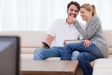 Lovely couple watching TV while eating popcorn clipart