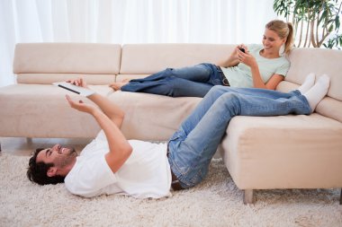 Woman using her smartphone while her boyfriend is using a tablet clipart