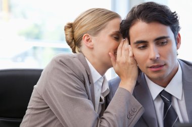 Businesswoman whispering something to her colleague clipart