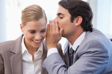 Businessman whispering something to his colleague clipart