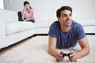 Man playing video games while his girlfriend is getting mad at h clipart