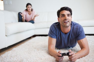 Man playing video games while his fiance is getting mad at him clipart