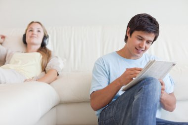 Man doing crosswords while his fiance is listening to music clipart