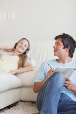 Portrait of a man doing crosswords while his girlfriend is liste clipart