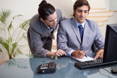 Businessman taking notes while getting mentored by colleague clipart