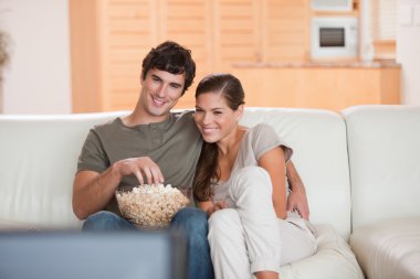 Couple with popcorn on the sofa watching a movie clipart