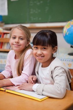 Portrait of smiling schoolgirls reading a fairy tale clipart