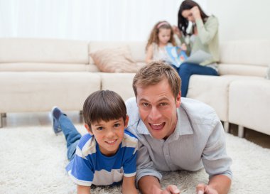 Dad and son lying on the carpet clipart