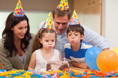 Boy helping his little sister to blow out the candles on her bir clipart