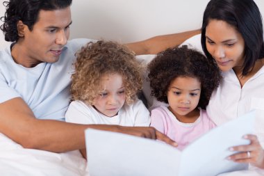 Parents reading a story for their children clipart