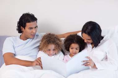 Parents reading a book with their children clipart