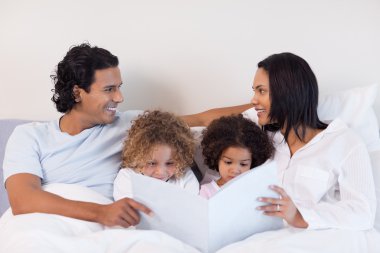 Family reading a story in the bedroom clipart