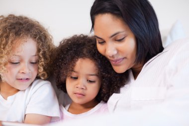 Woman sitting on the bed with her daughters clipart