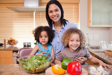 Mother and her daughters preparing salad in the kitchen together clipart