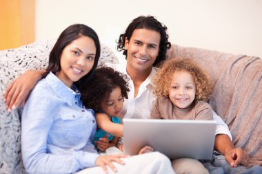 Family using laptop on the sofa together clipart