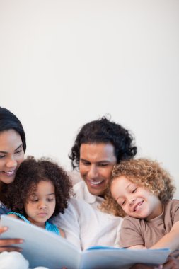 Cheerful family on the sofa looking at photo album together clipart