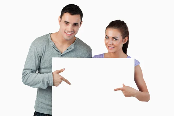 Giovane coppia indicando striscione di fronte a loro — Foto Stock