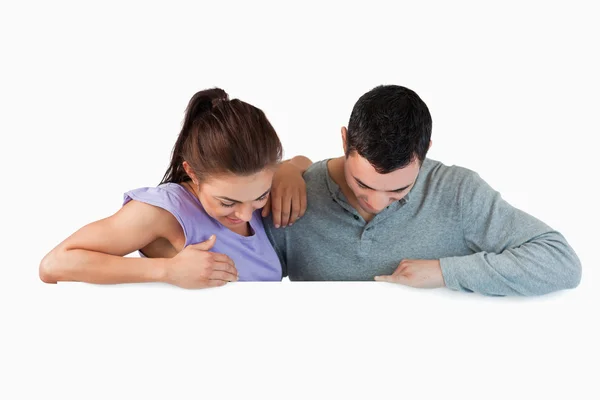 Young couple looking down a wall — Stock Photo, Image
