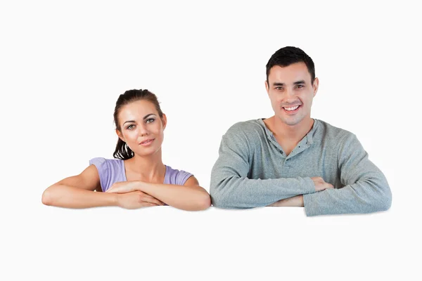 Smiling young couple looking over a wall — Stock Photo, Image