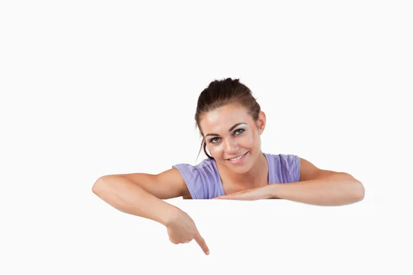 Young female pointing at banner below her — Stock Photo, Image