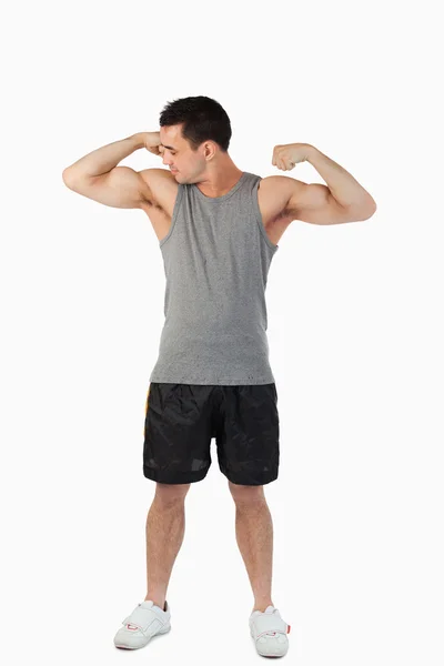 Jovem do sexo masculino olhando para seus músculos — Fotografia de Stock