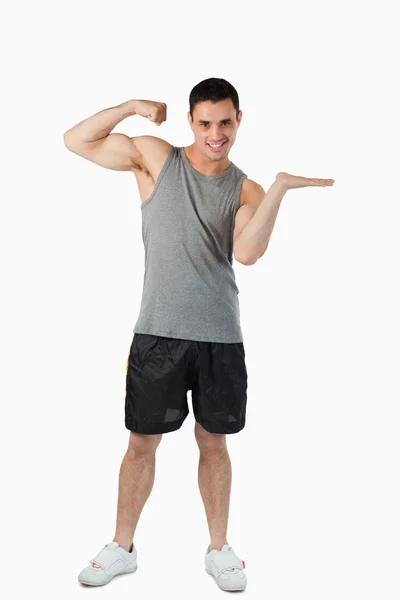 Mladý muž, ukazující jeho biceps během prezentace — Stock fotografie