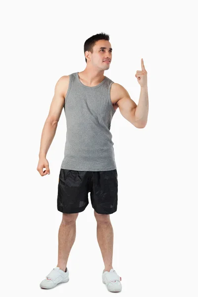 Молодой человек в спортивной одежде указывает вверх — стоковое фото