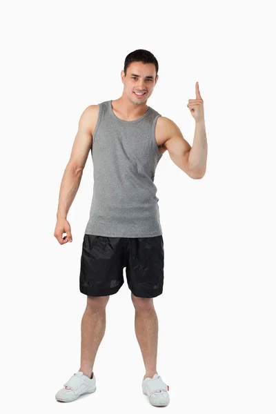 Young male in light sports cloths pointing upwards — Stock Photo, Image