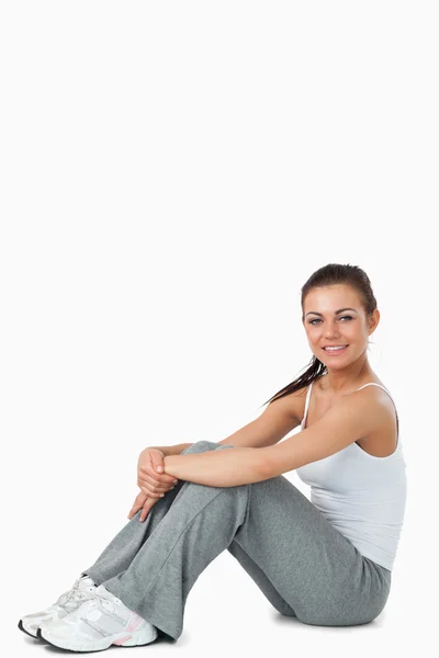 Junge Frau in Sportkleidung auf dem Boden sitzend — Stockfoto