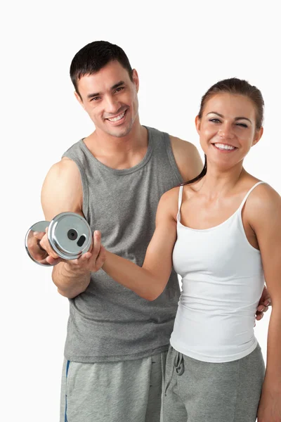 Portrait of a man helping a smiling woman to work out — Stock Photo, Image