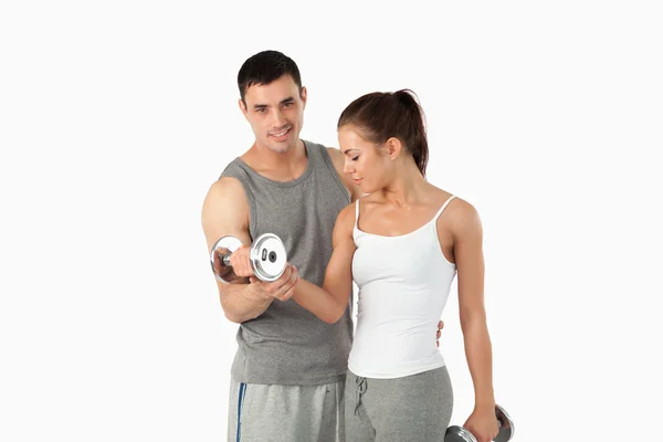 Hombre ayudando a una linda mujer a hacer ejercicio — Foto de Stock