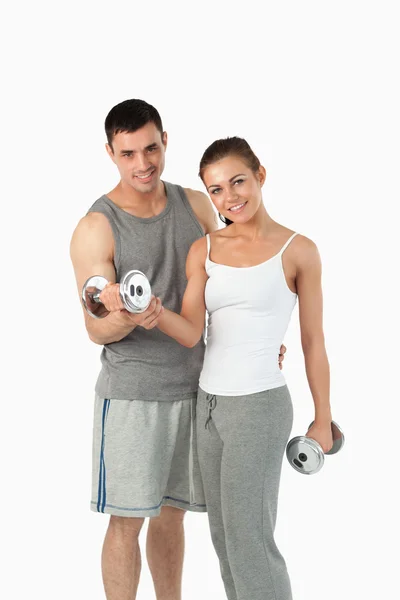 Portrait of a man helping a gorgeous woman to work out — Stock Photo, Image