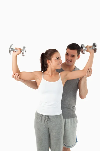 Portrait of a young man helping a smiling woman to work out — Stock Photo, Image